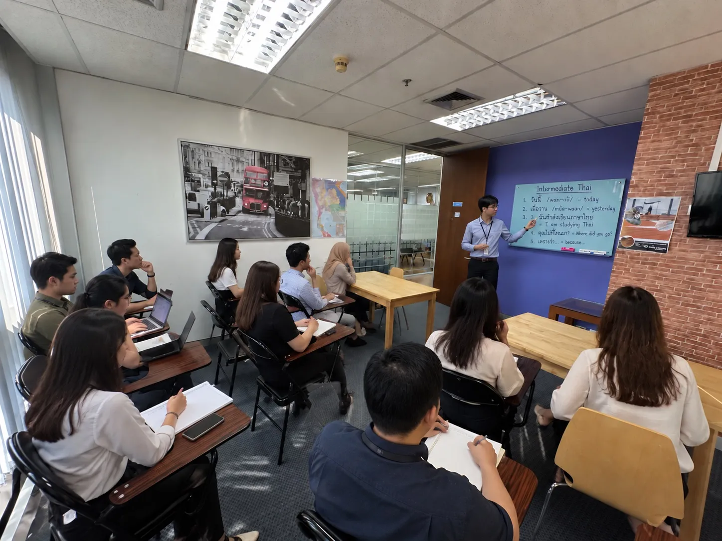 An intermediate Thai class at the school: the teacher points to Thai phrases on the screen while adult students take notes