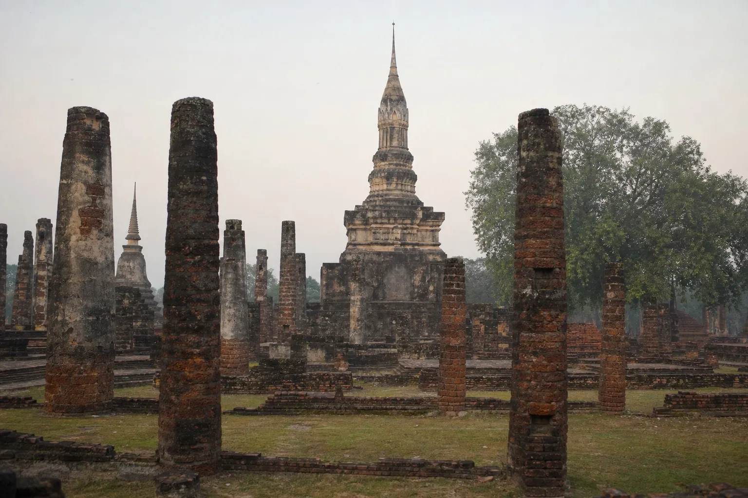 Weathered temple ruins at Sukhothai Historical Park in morning haze